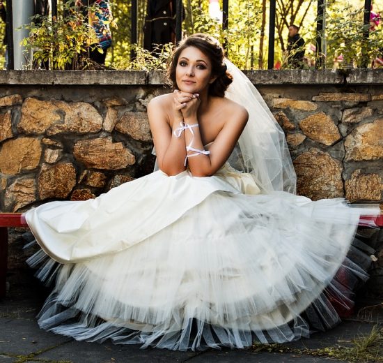 Bride in her wedding dress sitting on a park