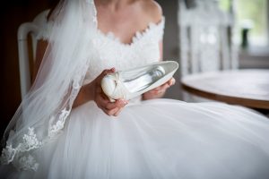 Bride in wedding dress holding her shoes