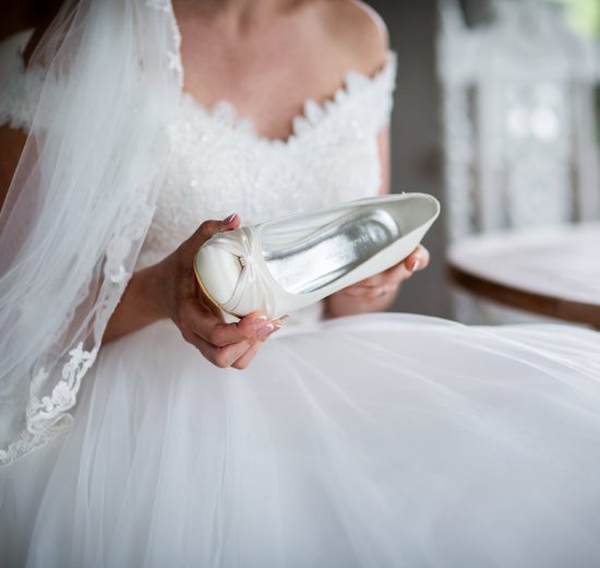 Bride in wedding dress holding her shoes