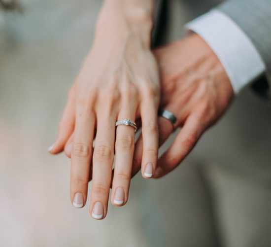 Couple's hand wearing white gold wedding rings