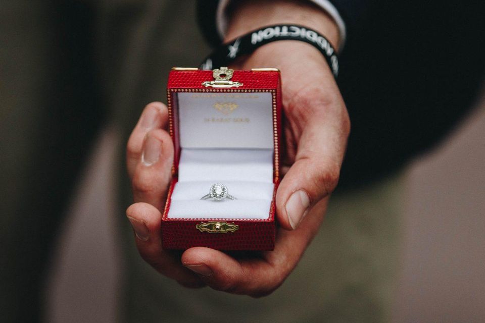 Man holding lab created diamond engagement ring in a red box