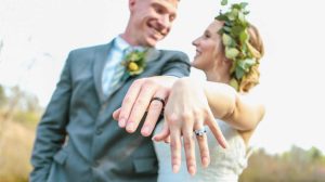 Groom wearing black wedding ring next to his bride