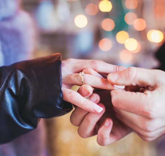 Man putting a cushion cut diamond ring on his girlfriend's hand