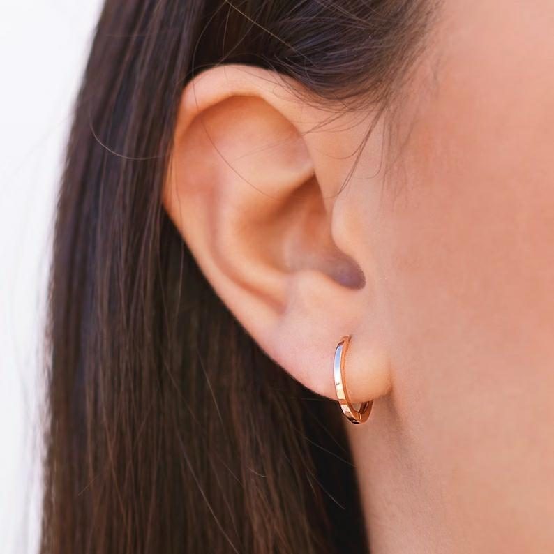 9k gold huggie hoop on the woman's ear